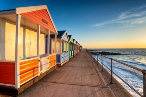 Une promenade en bord de mer, avec des cabanes de plage aux couleurs vives et une passerelle en bois.