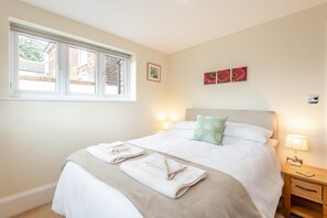 Une chambre à coucher comprenant un lit, deux tables de chevet, une fenêtre et des œuvres d’art murales.