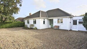 A single-story house with a gravel driveway, a green door, and a bench outside. - 3 Bed in Reydon (oc-hspind) (Reydon)