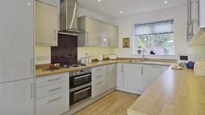A modern kitchen with white cabinets, stainless steel appliances, and a wooden countertop. - 3 Bed in Reydon (oc-hspind) (Reydon)