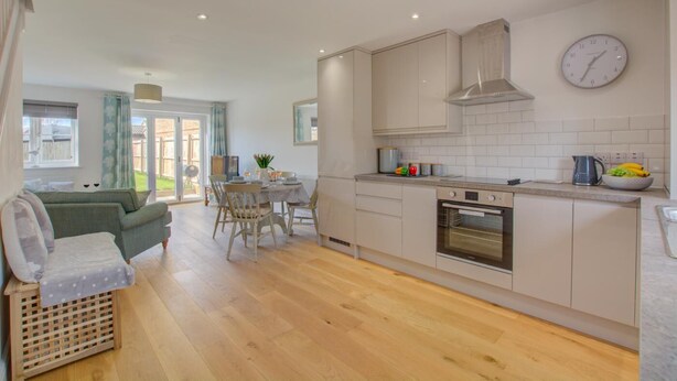 Een moderne keuken met een eethoek, houten vloeren en uitzicht op de omgeving.