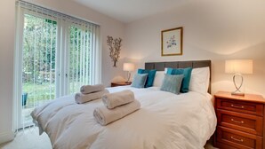 A bedroom with a large bed, two bedside tables, a nightstand, a window with blinds, and a framed picture on the wall. - 1 Bed in Belford (oc-nb677) (Belford)