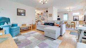A modern living room with a blue sofa, a grey sofa, a wooden dining table, and a chandelier. - 1 Bed in Belford (oc-nb677) (Belford)