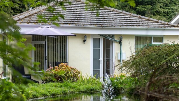 A house with a tiled roof, a door with a window, and a small garden with plants and a water feature. - 1 Bed in Belford (oc-nb677) (Belford)