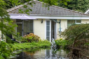 Una casa de techo de tejas, una puerta con ventana y un pequeño jardín con plantas y una fuente de agua.