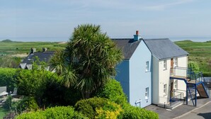 Ein Küstenhaus mit blauer Fassade, einer sichtbaren Treppe und Blick auf das Meer.