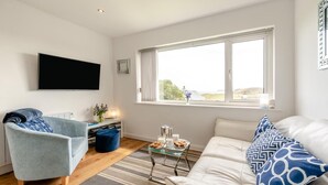 Ein modernes Wohnzimmer mit Sofa, Sessel und Couchtisch.