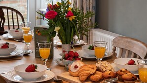 Ein Frühstückstisch mit Croissants, Muffins, Erdbeeren und Orangensaft.