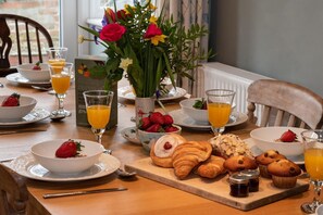 A breakfast setting with croissants, muffins, strawberries, and orange juice on a wooden table. - 4 Bed in Filey (oc-sa018) (Filey)