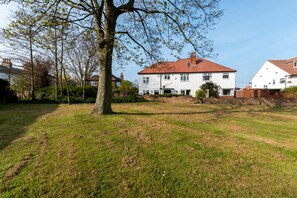 A residential area with a large white house with a red roof, surrounded by a grassy lawn and trees. - 4 Bed in Filey (oc-sa018) (Filey)