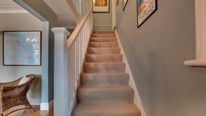 Eine Treppe mit Teppichstufen, weißen Geländern und einer Wand mit gerahmten Kunstwerken.