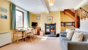 A cozy living room with a fireplace, a dining area with chairs and a table, and a bookshelf. - 2 Bed in Berwick-upon-Tweed (oc-nb678) (Lowick)