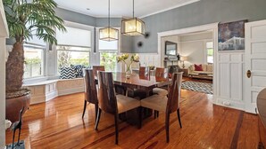 A dining area with a wooden table, chairs, and pendant lights. There is a potted plant and a decorative bird statue on the floor. - Historic Comfort l Walk to DNTN l Fire Pit (St. Augustine)