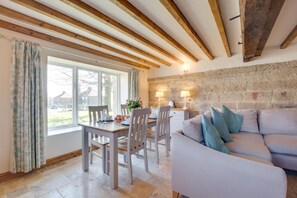 Ein Essbereich mit Tisch und Stühlen, einer Steinwand und einer Couch mit Kissen.