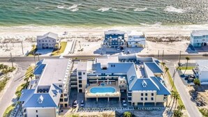 Un hotel frente al mar con varias construcciones, piscina y vistas a la playa.