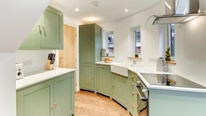 Eine moderne Küche mit grünen Schränken, einer weißen Arbeitsplatte und einem eingebauten Backofen.