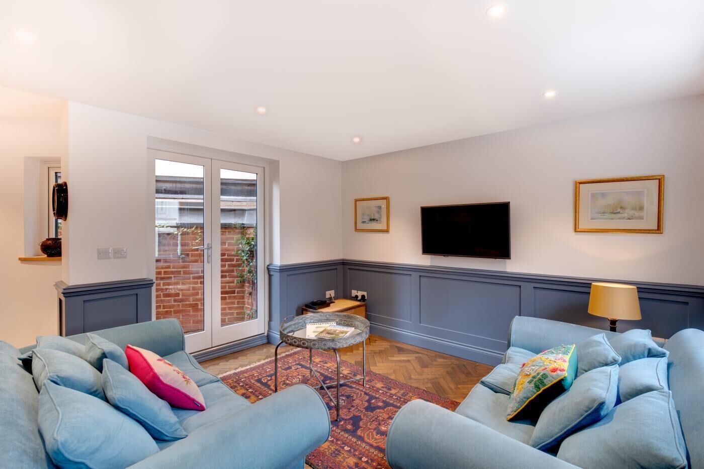 A living room with a sofa set, a coffee table, a TV, and a door leading to a balcony.