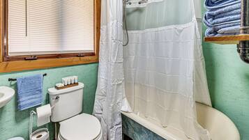 A bathroom with a toilet, sink, and shower curtain.