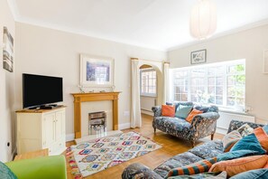 A living room with a fireplace, a television, a sofa, and a large window. - 3 Bed in Scarborough (oc-s018) (Scarborough)