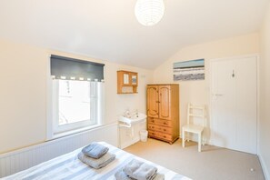 A bedroom with a bed, a window, a wooden wardrobe, a white chair, and a white bedside table. - 3 Bed in Scarborough (oc-s018) (Scarborough)