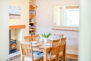 A dining area with a wooden table, chairs, and a fireplace. - 3 Bed in Scarborough (oc-s018) (Scarborough)