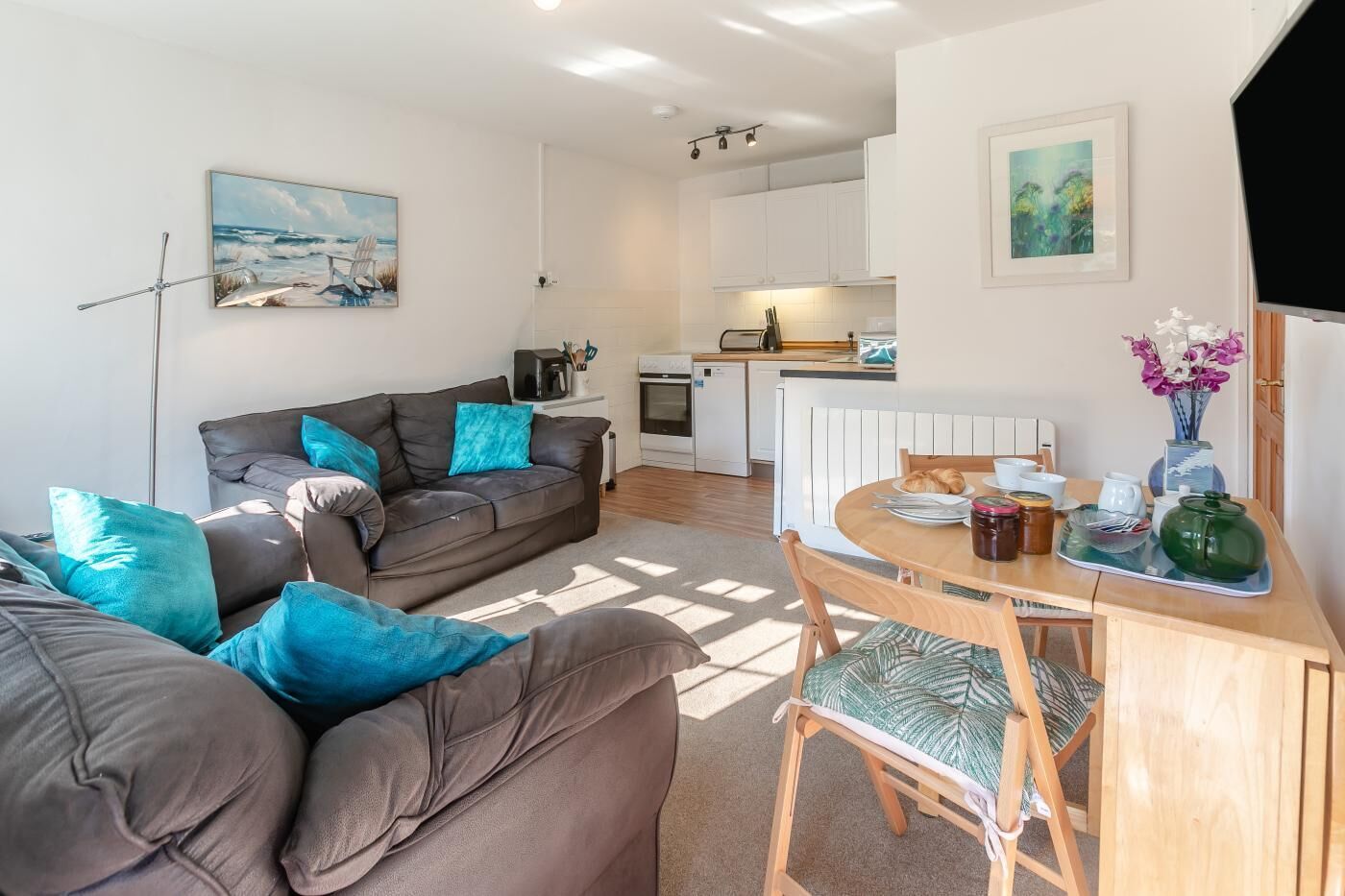 A modern living room with a sofa and a dining table set for breakfast.