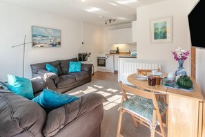 A modern living room with a sofa and a dining table set for breakfast.