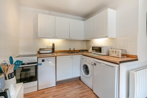 A compact kitchen with white cabinets, a microwave, a toaster, a dishwasher, and a washing machine. - 2 Bed in St. Keverne (oc-p00724) (Saint Keverne)