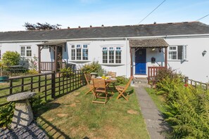 A white cottage with a blue door, a fenced garden, and a table with chairs. - 2 Bed in St. Keverne (oc-p00724) (Saint Keverne)