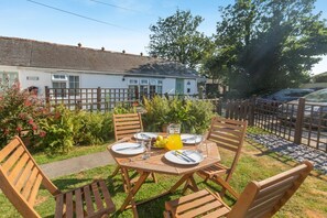 An outdoor dining area with a table set for four, surrounded by wooden chairs.