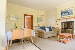 A dining area with a table set for two, a sofa, and a fireplace. - 1 Bed in Sizewell (oc-gdnf) (Sizewell)