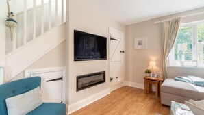 A room with a staircase, a fireplace, a bed, a table with a lamp, and a window with curtains. - 3 Bed in Beadnell (oc-44965) (Beadnell)