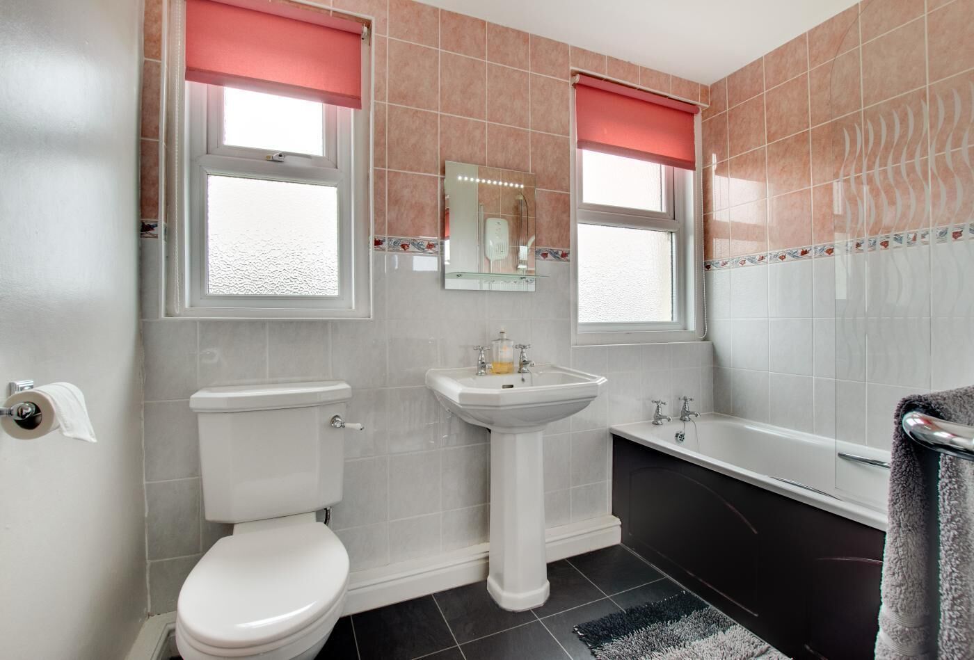 Et badeværelse med toilet, vask og badekar.