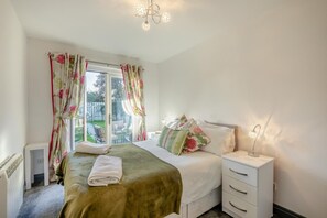 A bedroom with a bed, a bedside table, a lamp, and a view of the outside. - 2 Bed in Seahouses (oc-373002) (Seahouses)