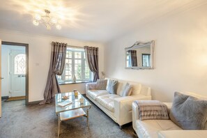 A living room with a sofa, a glass coffee table, and a chandelier. - 2 Bed in Seahouses (oc-373002) (Seahouses)