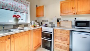 Une cuisine avec des meubles de rangement en bois, un four à micro-ondes, un grille-pain et un évier.