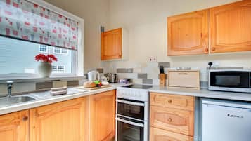 A kitchen with wooden cabinets, a microwave, a toaster, and a stove.
