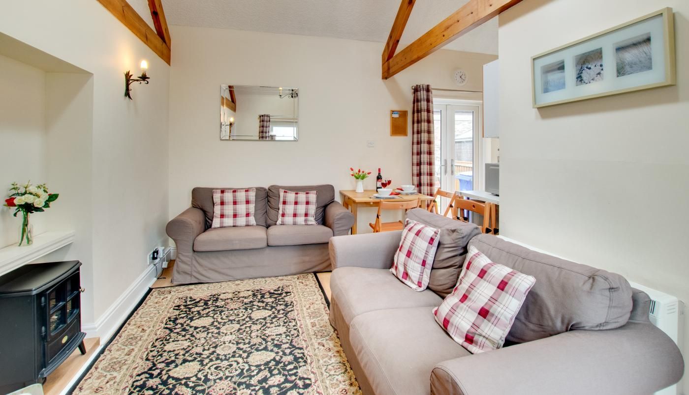 A living room with a sofa set, a rug, a fireplace, and a dining area with a table and chairs.