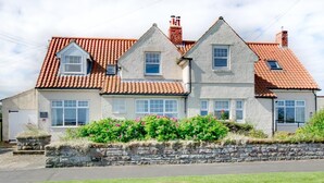 A two-story house with a red-tiled roof, stone walls, and a stone wall in front. - 2 Bed in Beadnell (oc-30053) (Beadnell)