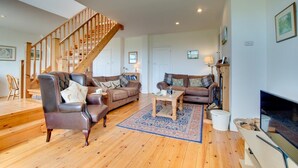 A spacious living room with a wooden staircase, two sofas, a coffee table, and a fireplace. - 2 Bed in Beadnell (oc-30053) (Beadnell)