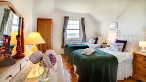 A bedroom with two beds, a wooden wardrobe, a mirror, and a window with curtains. - 2 Bed in Beadnell (oc-30053) (Beadnell)