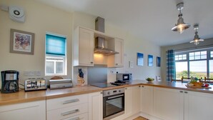 Una cocina moderna con gabinetes blancos, horno integrado, tostadora y ventana con vistas.