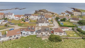 Un área residencial costera con casas, una calle y vistas al mar.