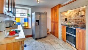 Eine Küche mit Kühlschrank, Backofen und Holzschränken.