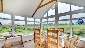 A conservatory with a table set for dining, large windows, and a view of the countryside. - 2 Bed in Belford (oc-79885) (Belford)