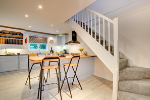 Eine moderne Küche mit Kochinsel, Barhocker und einer Treppe.