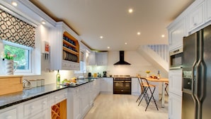 Uma cozinha moderna com armários brancos, forno embutido e sala de jantar com mesa e cadeiras de madeira.