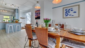 Un comedor con una mesa de madera dispuesta para cuatro personas, rodeada de sillas de mimbre.