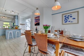 Un coin repas avec une table en bois dressée pour quatre personnes, entourée de chaises en osier.