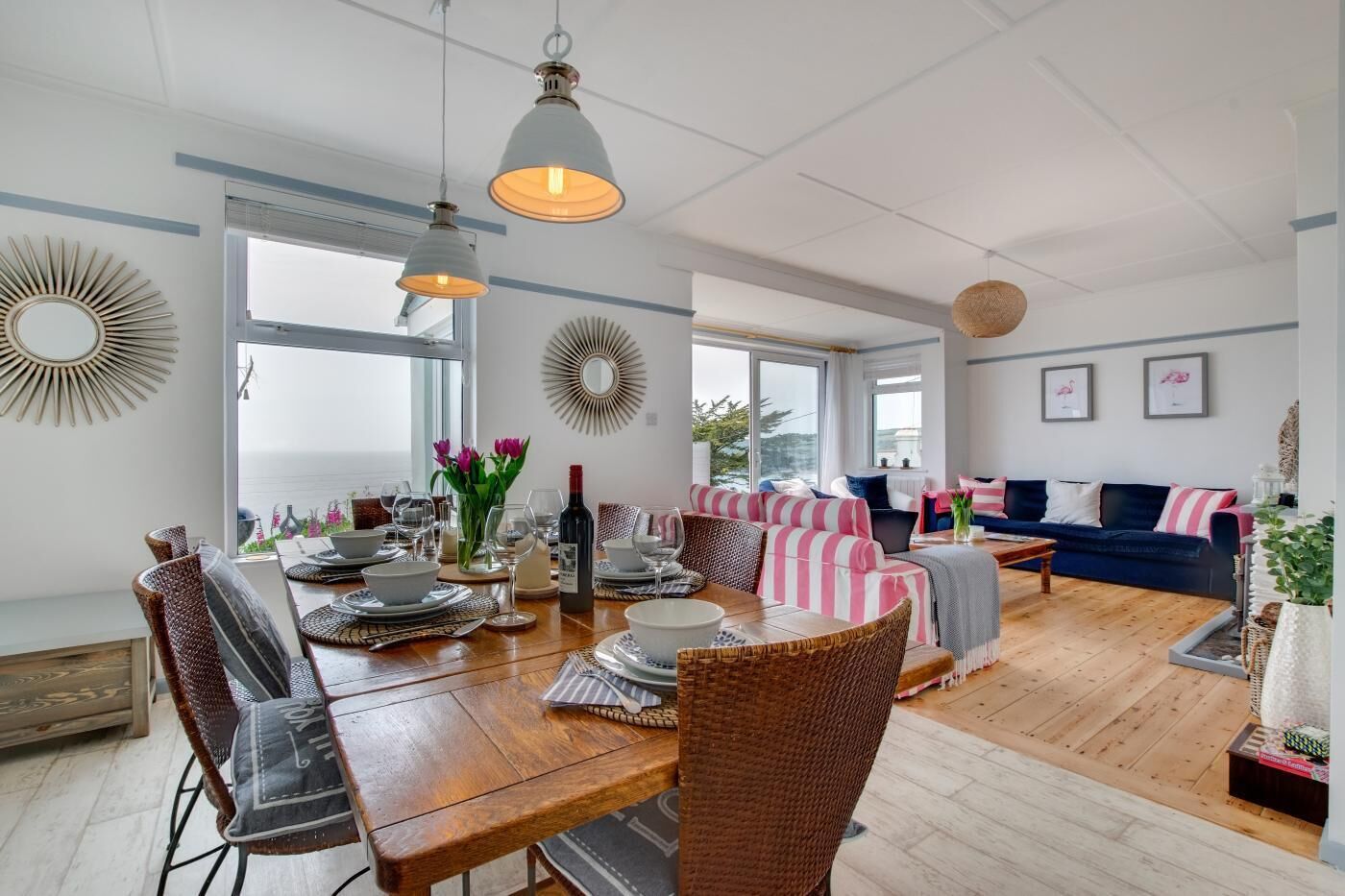 A spacious living area with a dining table set for a meal, a sofa, and a view of the outdoors.